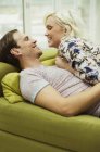 Affectionate couple laying on living room sofa face to face — Stock Photo