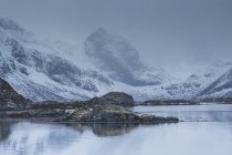 Snow covered craggy mountains over cold bay, Norway — Stock Photo