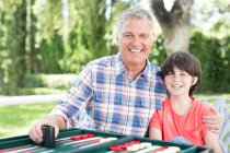 Abuelo y nieto jugando backgammon en el patio - foto de stock