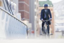 Бизнесмен в костюме и шлеме катается на велосипеде в городе — стоковое фото