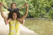 Portrait playful mother carrying son on shoulders near pond — Stock Photo