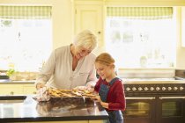 Grandmother and granddaughter baking gingerbread cookies in kitchen — Stock Photo