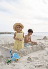 Children building sandcastle on beach — Stock Photo