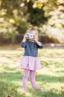 Toddler girl using retro camera in autumn park — Stock Photo