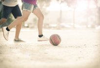 Enfants jouant avec le ballon de football dans le sable — Photo de stock