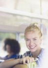 Portrait femme blonde souriante tenant un téléphone portable dans le bus — Photo de stock