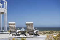 Lounge chairs on patio overlooking ocean — Stock Photo