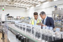 Supervisor und Manager beobachten Plastikflaschen auf Förderband — Stockfoto