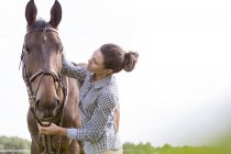 Woman petting horse at pasture — Stock Photo