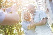 Man photographing senior couple outdoors — Stock Photo