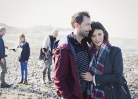 Портретна пара обіймається сонячно кам'янистим пляжем — стокове фото
