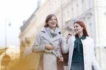 Smiling women carrying shopping bags in city — Stock Photo