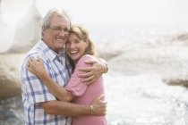 Coppia più anziana che si abbraccia sulla spiaggia — Foto stock