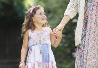Smiling girl in dress holding mother's hand — Stock Photo