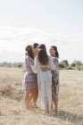 Boho mulheres abraçando em um círculo no campo rural ensolarado — Fotografia de Stock