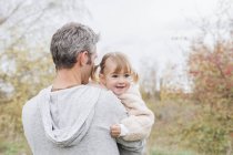 Father holding smiling toddler girl in park — Stock Photo