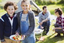 Portrait smiling brother and sister with vegetable skewers at campsite — Stock Photo