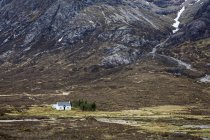 House in remote valley below craggy mountains, Glencoe, Scotland — Stock Photo