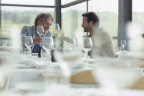 Männer stoßen am Restauranttisch auf Weingläser an — Stockfoto