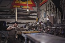 Herrero trabajando en forja en interiores - foto de stock