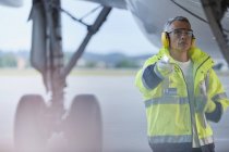 Air traffic controller with flashlight under airplane on airport tarmac — Stock Photo