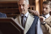 Tailor fitting businessman for suit in menswear shop — Stock Photo