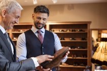 Рабочий, показывающий туфли бизнесмену в магазине мужской одежды — стоковое фото