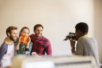 Творческие бизнесмены игриво позируют коллеге с мгновенной камерой — стоковое фото