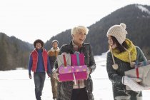 Friends carrying Christmas gifts in snow — Stock Photo