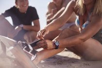 Закройте женщину крепя кайтборд к ногам на пляже — стоковое фото