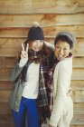 Portrait smiling female friends gesturing peace sign outside cabin — Stock Photo