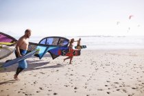 Amigos correndo com kiteboarding pipas na praia ensolarada — Fotografia de Stock