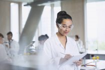 Female college student taking notes in science laboratory classroom — Stock Photo