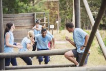 Teammates cheering man on boot camp obstacle course — Stock Photo