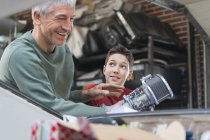 Усміхнений батько і син ремонтують автомобільний двигун в авторемонтному магазині — стокове фото
