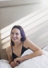 Femme souriante couchée au lit regardant ailleurs — Photo de stock
