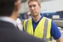Serious worker listening to manager in steel factory — Stock Photo