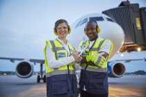 Portrait confident air traffic control ground crew workers near airplane on airport tarmac — Stock Photo