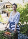 Portrait smiling woman harvesting carrots in garden — Stock Photo