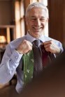 Uomo d'affari sorridente che prova cravatte nello specchio al negozio di abbigliamento maschile — Foto stock