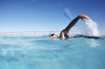 Male swimmer athlete swimming in sunny swimming pool — Stock Photo
