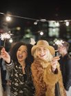 Young women waving sparklers at rooftop party — Stock Photo
