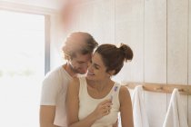 Liebevolles Paar beim Zähneputzen im sonnigen Badezimmer — Stockfoto