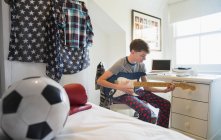 Хлопчик грає на електрогітарі в спальні — стокове фото