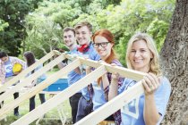 Portrait of smiling volunteers lifting construction frame — Stock Photo