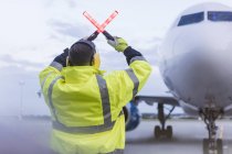 Air traffic controller guiding airplane with wand lights on tarmac — Stock Photo
