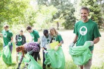 Portrait of smiling environmentalist volunteer picking up trash — Stock Photo