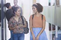 Smiling female college students walking in corridor — Stock Photo