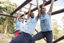 People crossing monkey bars on boot camp obstacle course — Stock Photo
