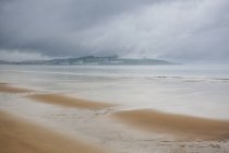 Plage de sable avec de l'eau ondulée pendant la journée — Photo de stock